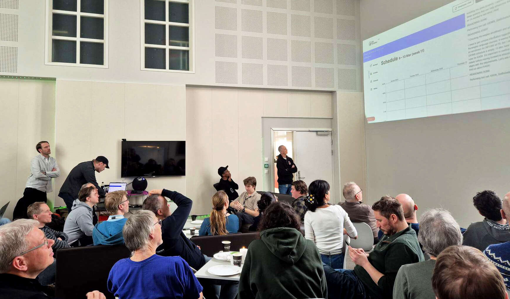 Mange mennesker i en forsamling følger med på en presentasjon
